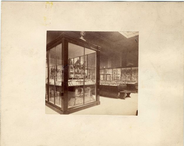 Installation. Black and white photograph of paintings and fragments thereof displayed in wood and glass cases.