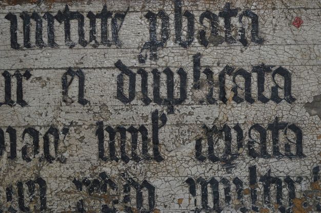 Painting. Detail view of black letters along dark incised guidelines incised into the white ground.