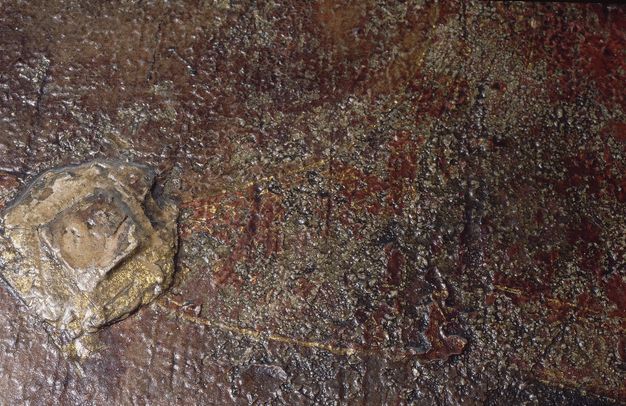 Painting. Detail view of a diamond-shaped object in low relief is gilded, as are thin lines emanating from it. The rest of the paint appears textured with burgundy red and grey.