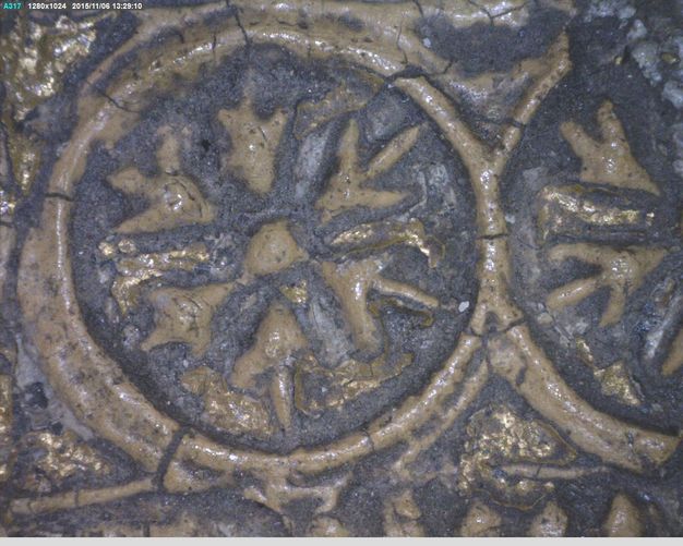 Relief. Detail view of a roundel in relief with an arrowhead-pattern. The raised areas are tan coloured, and some have some gold leaf remaining. The rest is indigo blue.