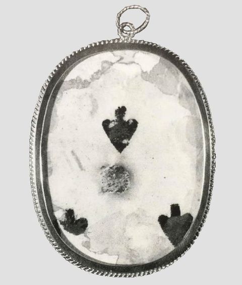 Playing card. The centre of a playing card with three black spades visible here is set in an oval frame and covered with glass or other clear material.
