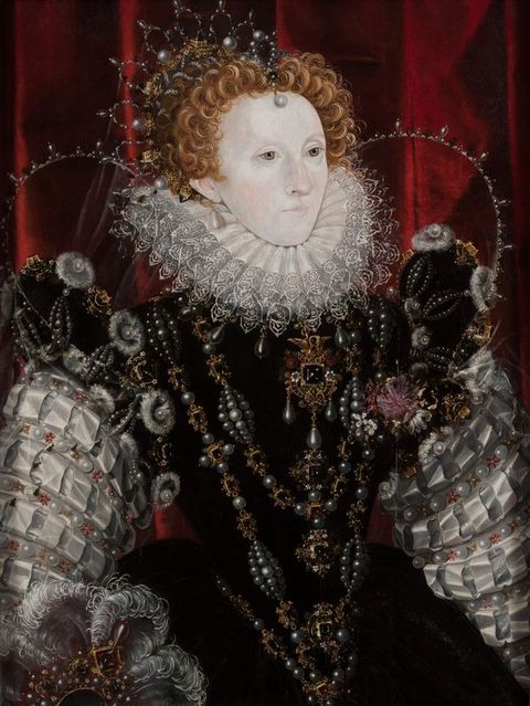 Painting. A smooth-skinned woman with a powder-white face touched with pink at the cheeks and nose is shown from the hips up in front of a ruby-red curtain. She is angled to our right and looks in that direction with hazel eyes. The crown in her copper-red curls, her jewellery, and dress glisten with gold, gems, and pearls.