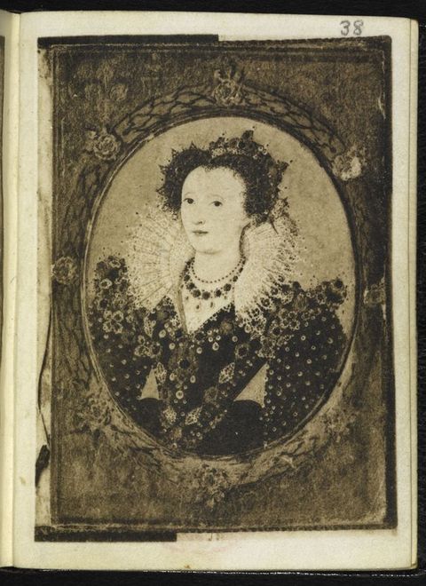Painting. Black and white facsimile of a page from a book. A portrait of a pale-skinned woman with dark eyes is in an oval frame. A lacy, pleated ruff lines the back of her neckline, which meets in a V beneath jewelled necklaces. Her crown and gown are covered with pearls and gems.