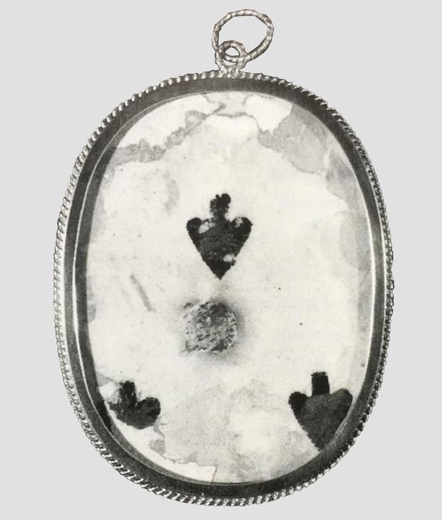 Playing card. The centre of a playing card with three black spades visible here is set in an oval frame and covered with glass or other clear material.