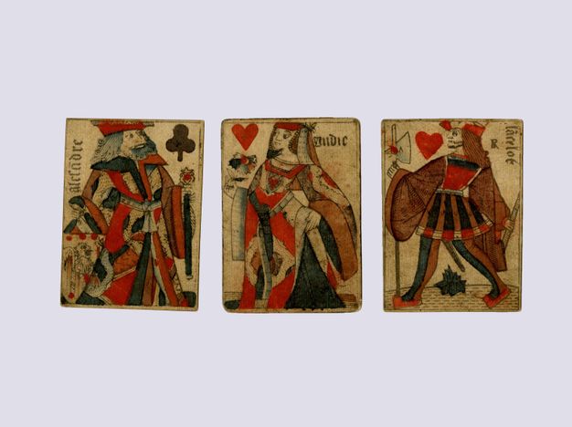 Playing cards. Three cards are printed and hand-coloured with red, dark blue, and brown. They show the king of clubs, the queen of hearts, and the knave of hearts.
