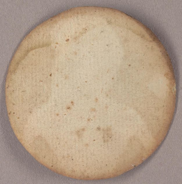 View of the back of a round portrait painting, which has been affixed to paper, now yellowed and water stained across the top. The outline and shape of the woman on the other side is visible.