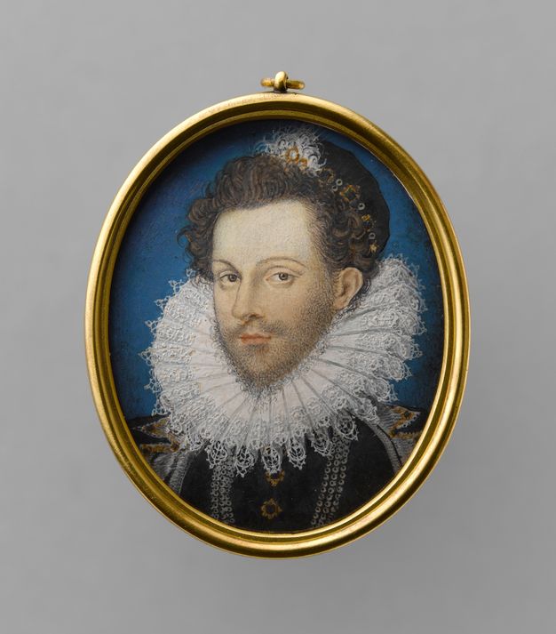 Watercolour. A pale-skinned man with loose, brown curls looks at us from the corners of brown eyes under arched brows. A smile begins to play on his narrow lips. He has a wispy beard framed by pleated lacy ruff, which tucks up under his chin and around the back of his head. He is against a blue background and set into a gold, oval frame.