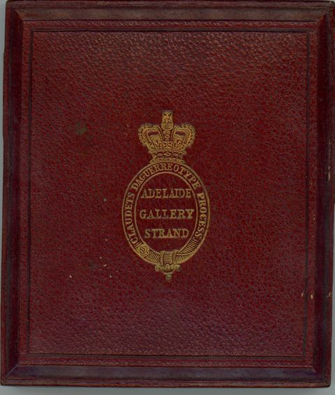 Burgundy-red leather case is stamped with a gold insignia of a crown over an oval cartouche.