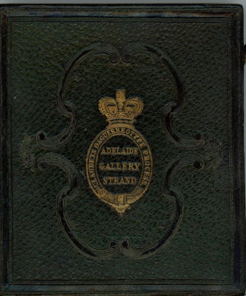 Forest-green leather case is stamped with a gold insignia of a crown over an oval cartouche. The insignia is surrounded by a tooled ornamental design of parentheses-shaped bands.