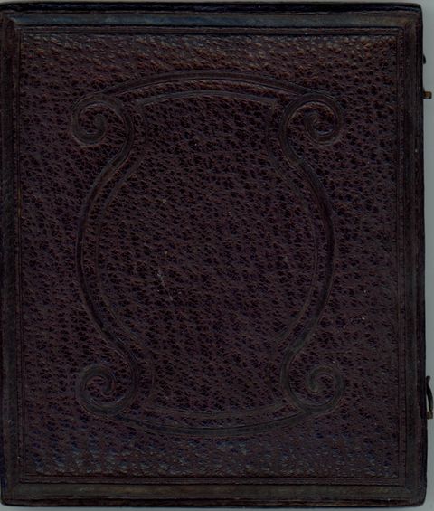 Dark brown leather case is tooled with ornamental design of parentheses-shaped bands.