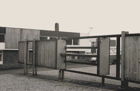 Architecture. A wall-like structure alternates sections of vertical panelling with empty space and horizontal boards in this black and white photograph.