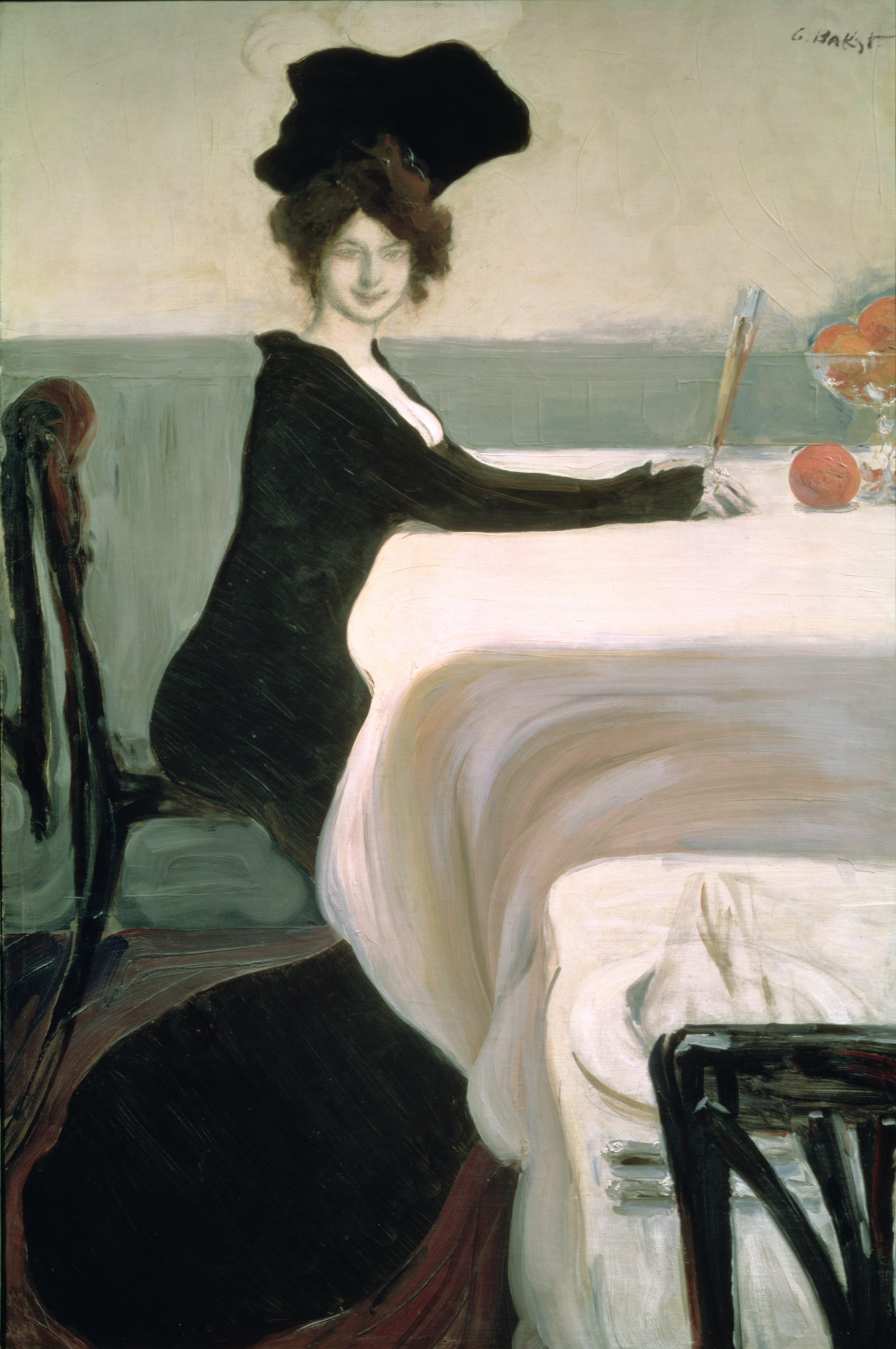 Painting. A woman’s black dress oozes down her arms, body, and onto the floor like an ink spot. Her skin is ashy white and her hair a fuzzy mass of dark brown under a flat, black hat. She sits at a white tablecloth, arms stretched in front of her, facing our right in profile. Her face turns, and she smiles archly out at us.