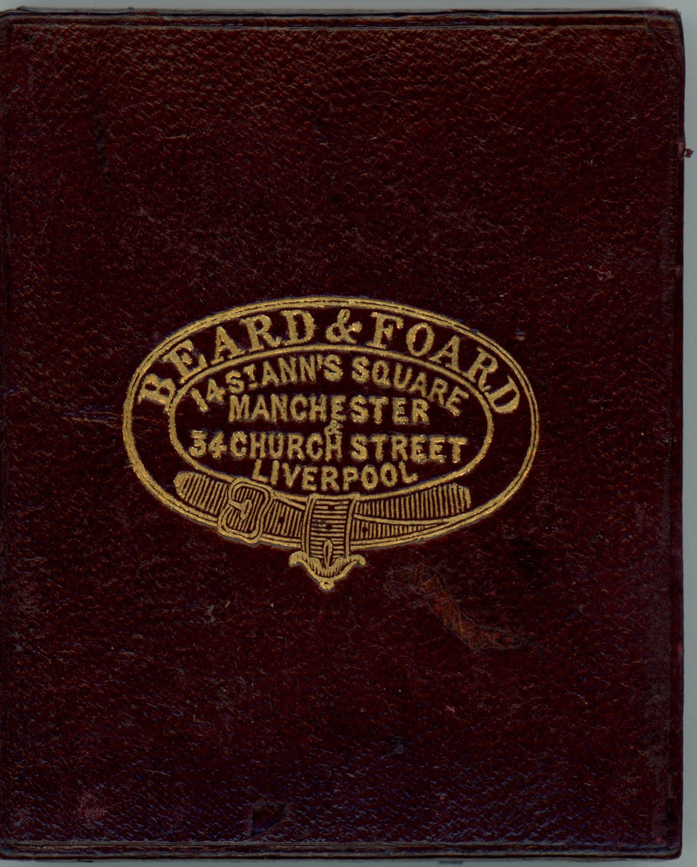 Case. Burgundy-red leather case is stamped with a gold insignia and text.