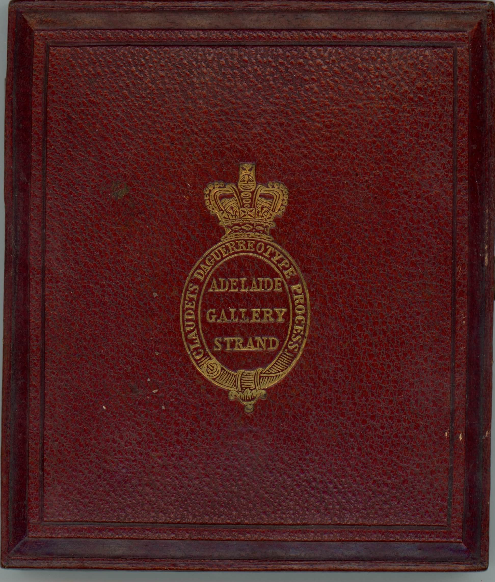 Burgundy-red leather case is stamped with a gold insignia of a crown over an oval cartouche.