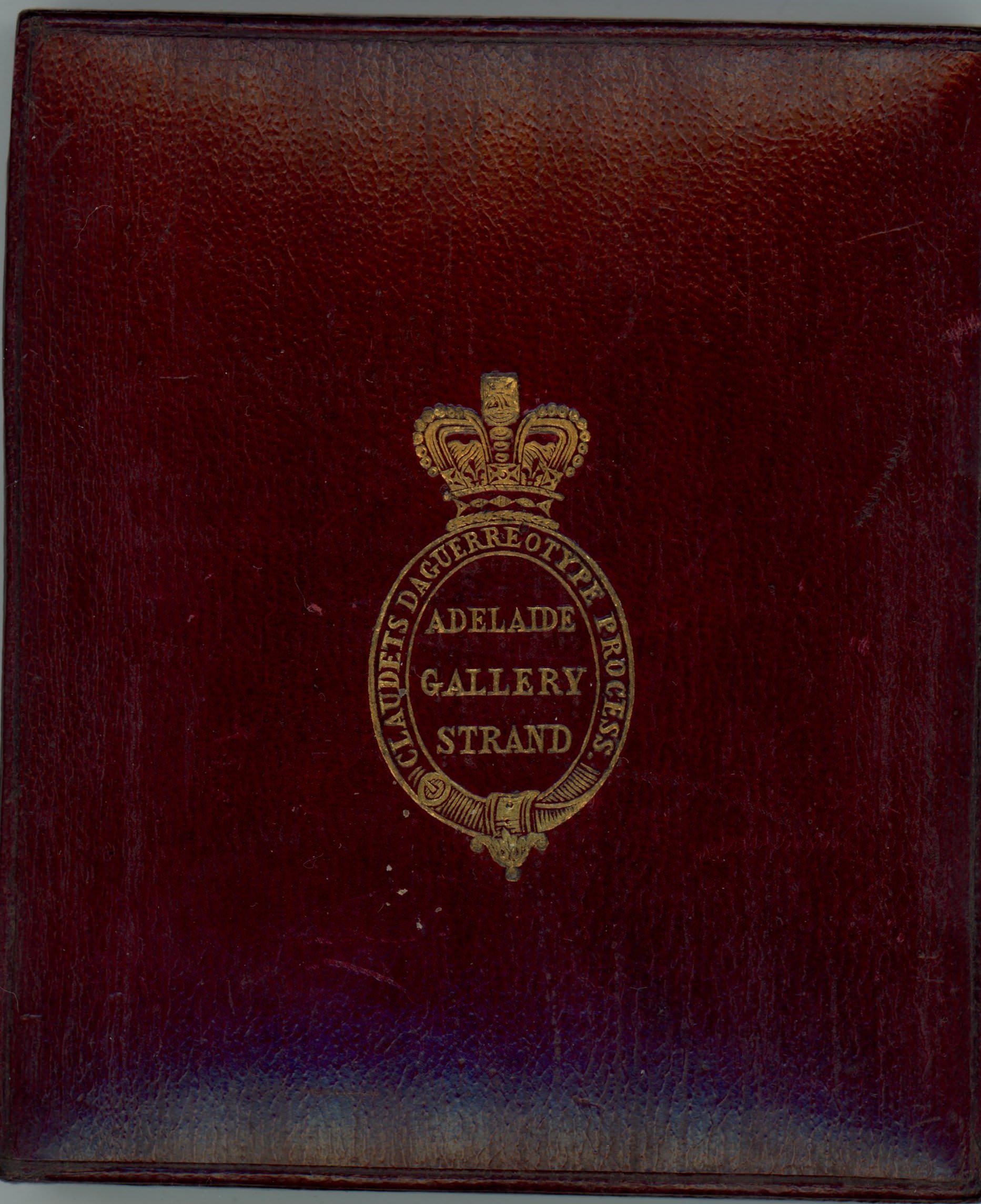 Burgundy-red leather case is stamped with a gold insignia of a crown over an oval cartouche.