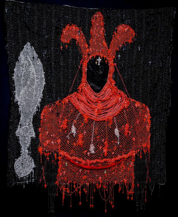 Mixed media. A red silhouette of a costume seems drawn in thread against a black background. The hood has three tall lobes. Tiny red crosses and a few sculptures hang all over the costume. A silvery grey object with a blade-like form above a circle is to the left.
