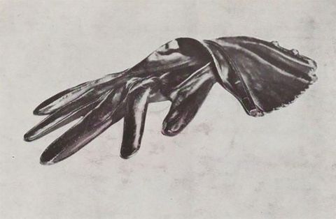 Black and white photograph. A silky black glove lies sensuously limp against a blank white background.