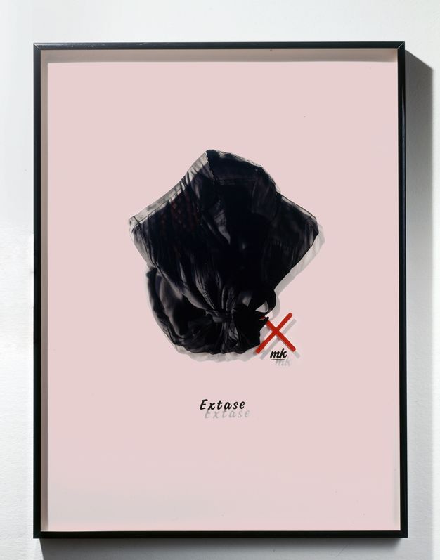 Mixed media. A photograph of a black, collared woman’s shirt or robe has been printed onto a piece of Plexiglass and mounted in a frame so it casts a shadow on the pastel pink mat behind it, creating double vision. The word “Extase” is below.
