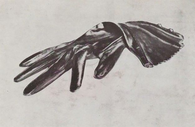 Black and white photograph. A silky black glove lies sensuously limp against a blank white background.