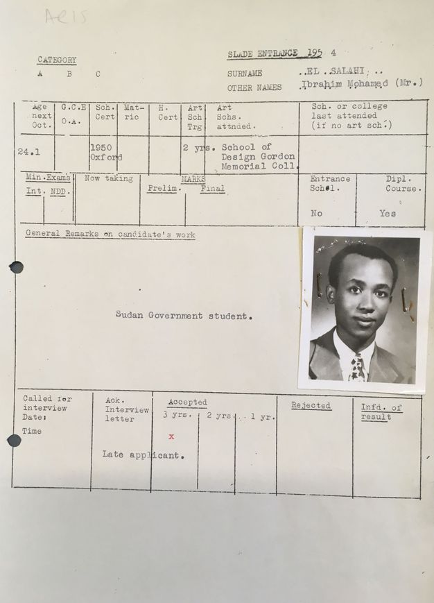 Typewritten form. A passport-sized, black and white photograph of Ibrahim El-Salahi wearing a suit and tie is stapled to a school form. Slightly smiling, he has dark skin, short black hair, a high forehead, and a pointed chin.