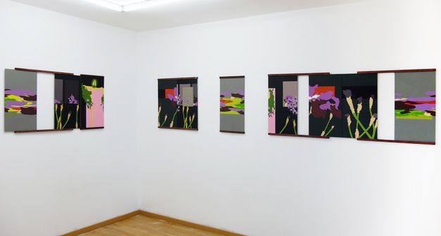 Installation photograph. Seven rectangular or square panels are painted with abstract designs in flat areas of grey, black, bright yellow, violet, red, green, brown, or black. Some forms are reminiscent of flowers. The panels are held by what appears to be rails supporting the tops and bottoms.