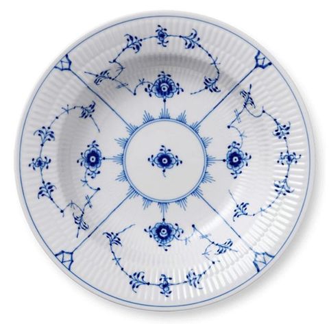 Porcelain. A white plate with ridged edges is painted with an ink-blue design of flowers and vines in a geometric pattern.