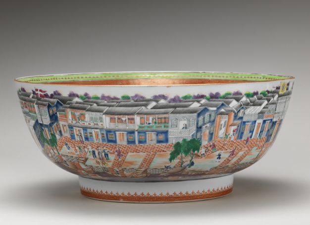 Porcelain. A wide bowl sits on a low, straight-sided foot. The outside of the bowl is painted with buildings lining a street with people.