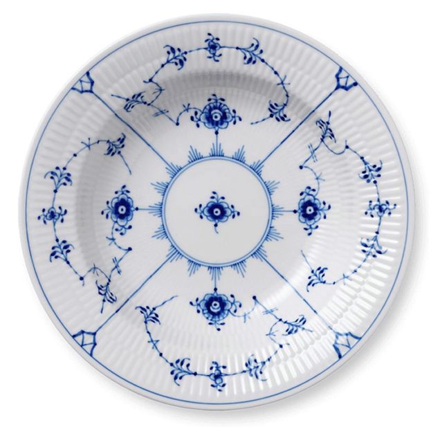 Porcelain. A white plate with ridged edges is painted with an ink-blue design of flowers and vines in a geometric pattern.