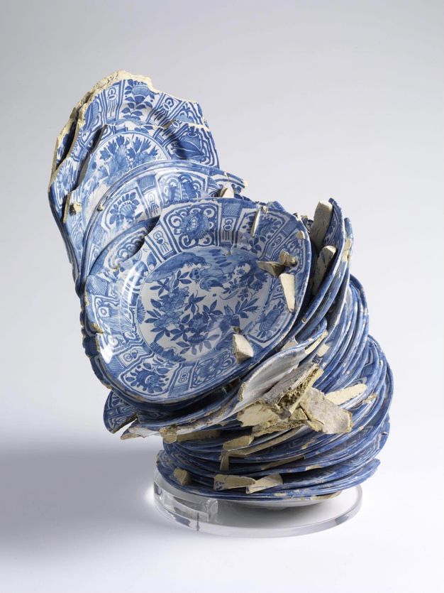 Porcelain. Thirty-four white porcelain plates painted with blue designs are fused together in a leaning tower that seems ready to slide apart at any moment.