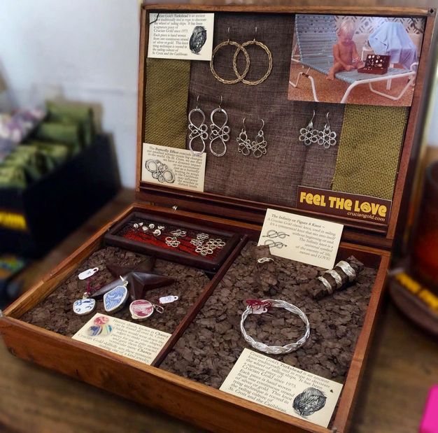 An open wooden case displays earrings, a bracelet, rings, and pendants. The latter are made from fragments of blue or red and white porcelain.