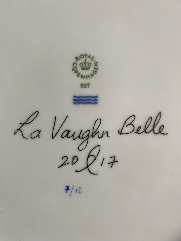 Plate. Detail view of the underside of a white porcelain plate. An insignia for Royal Copenhagen is above La Vaughn Belle’s signature and the date. The plate is numbered below, “7/12”.