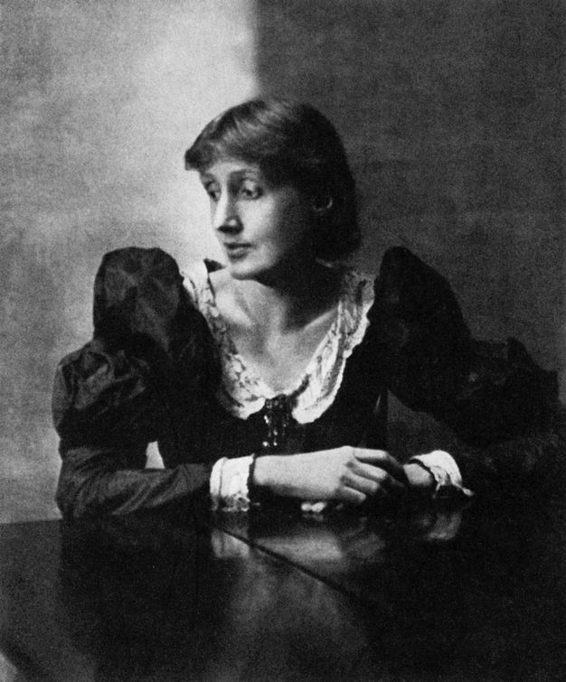 Black and white photograph. A pale-skinned woman with wide-set eyes sits on a throne. Her lace-edged gown drips with pearls and gems.