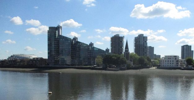 Across a river from us, high-rise buildings and one with a roofline that angles up to our left are outlined against a blue sky.
