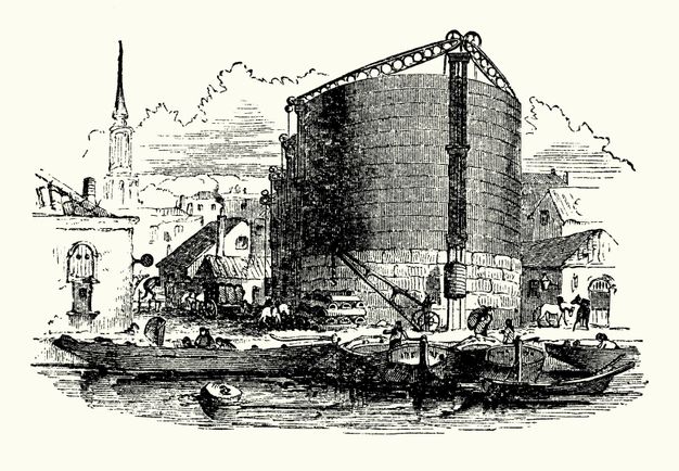 Print. Boats line up at a dock in front of a round, silo-like building. More structures as well as people and horses surround it, and a church steeple rises in the distance of this black and white engraving.