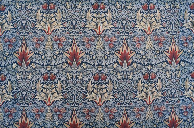Textile. Sky-blue leaves and vines create intricate, curling patterns around cream-white, brick red, and muted pink flowers. The background is navy blue.