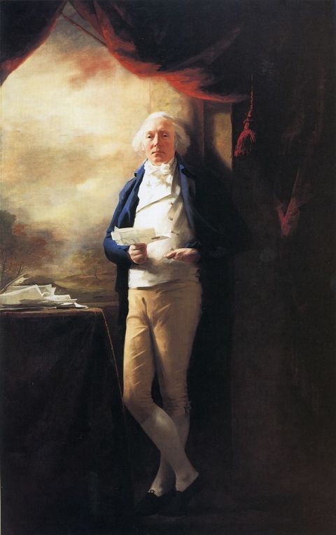 Painting. A pale-skinned man with white hair and rosy cheeks stands with his ankles crossed, leaning against a window frame in this full-length portrait. He holds an opened letter in one hand, and the other tucks into the pocket of his white vest.