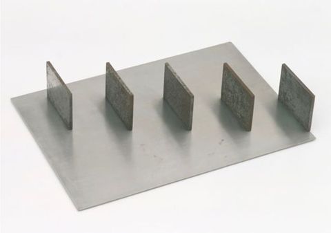 Sculpture. Five metal panels are spaced along a rectangular steel sheet to create a diagonal from one corner to the other. The panels are parallel to each other, like staggered equal signs.