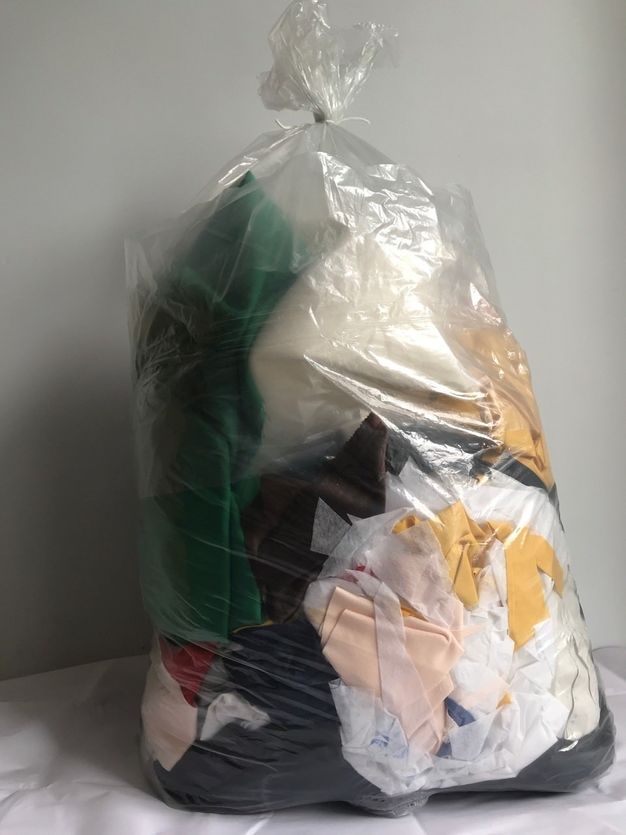 Sculpture. A clear plastic bag is filled with scraps or pieces of cloth and then tied at the top.