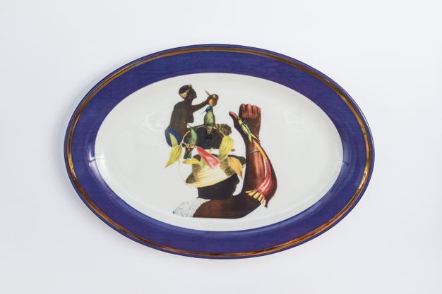 Porcelain. Two dark-skinned women appear collaged with floral elements at the centre of this white oval plate. The cobalt-blue rim is edged in gold.