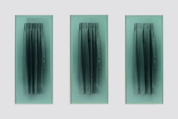 Multimedia. Three black and white photographs each show a curtain four pleats wide. Each is then covered with a sheet of seafoam-green glass and hung on a white gallery wall.