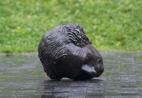The bronze head of a statue is padded in layers of foam and blankets, and is strapped to the flatbed of a truck.