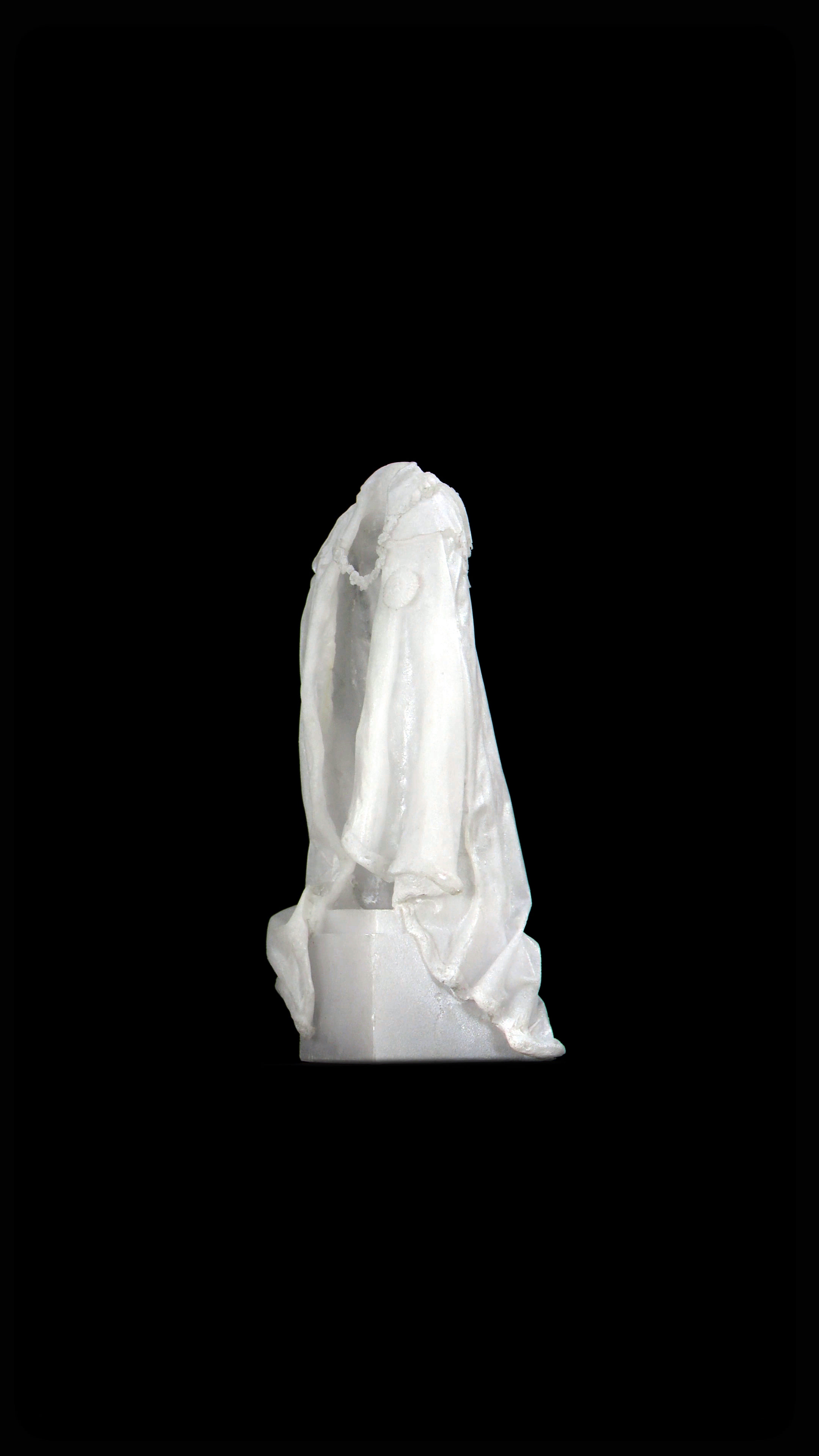 Video still. A white cloak hangs as if over someone’s shoulders, but is empty. The opening is angled to our left against a black background.