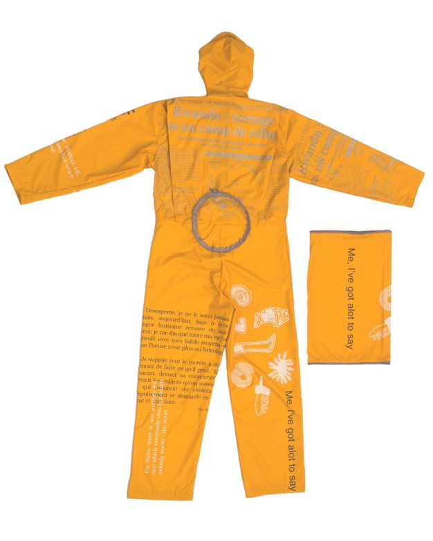 Textile. An orange suit is printed with white symbols and grey and black text. A rectangular piece next to it is printed with 'Me, I've got a lot to say'.