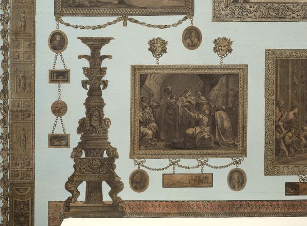Installation. Detail view of one large rectangular print surrounded by ten smaller medallion or rectangles. Most seem to hang from chains against a pale blue wall.