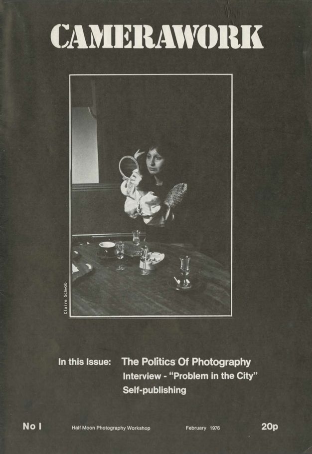 Black magazine cover with white text and a black and white portrait format photograph inside a thin white border. The word "Camerwork" appears in large text at the top. The photo shows a woman sitting at a dining table, looking at herself in a circular mirror. The table is set with dishes and glasses. The cover text highlights features such as "The Politics of Photography" and an interview titled "Problem in the City". It is priced at 20p.