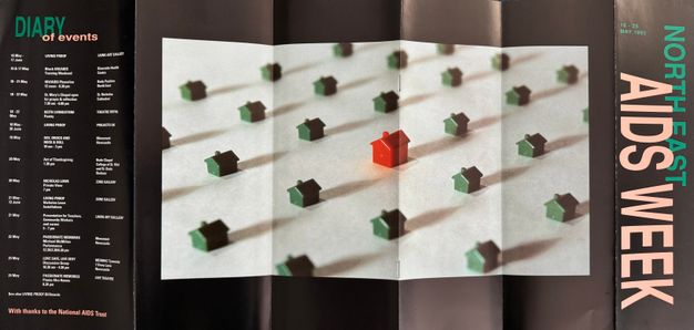 A colour photograph of a flyer advertising North East AIDS Week, May 1992. The flyer features a photograph of a Monopoly game pieces, with one piece representing a person with AIDS. The flyer includes information about the events taking place during the week, including a candlelit vigil, a performance by the Promo Afros Homos.