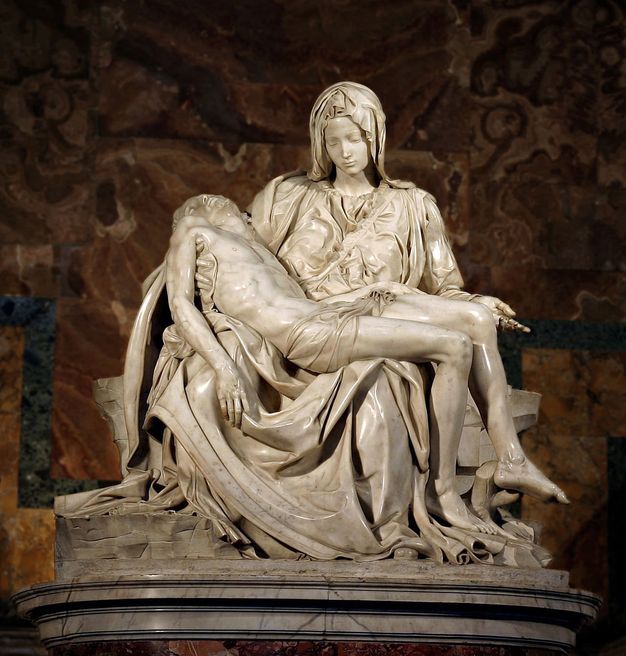 Sculpture. Carved from marble, a seated woman has a man's limp and lifeless body draped across her lap. He is almost naked, apart from a small loin cloth, while she is draped in yards of loose-fitting fabric that spills out onto the floor around them. Her head is tilted downwards towards him.