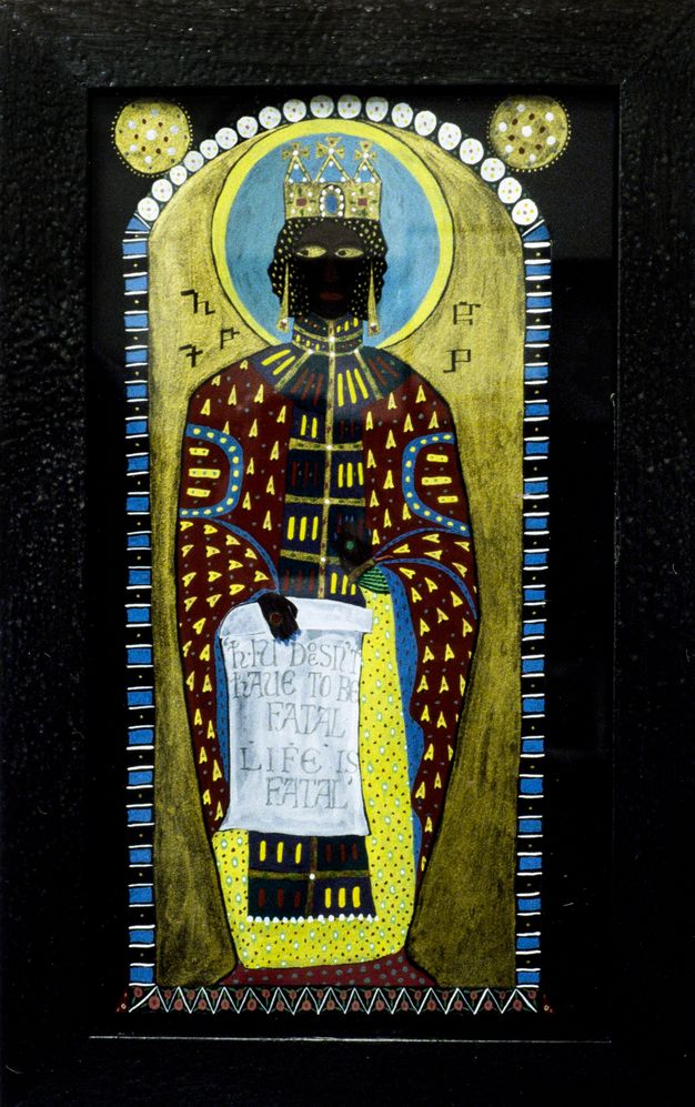 Installation photograph. A tall figure with a dark skin tone is dressed in patterned clothing, wears a gold crown, and holds a scroll that includes the text, “LIFE IS FATAL”. They stand against a gold backdrop, with a blue circular halo behind their head. Around the artwork is a colourful, patterned frame made up of stripes, circles and zig zags.
