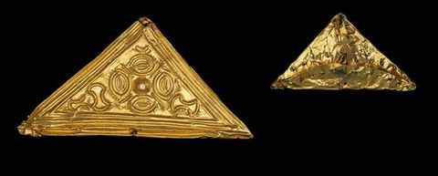 Colour photograph. Documentation of two golden, triangular objects. The larger one is seen from the front, and contains a series of detailed patterns carved into its surface, while the other is seen from behind, with visibly rough, overlapping edges of metal folded over one another.