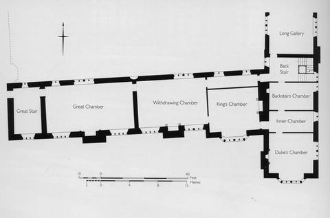 Black and white photograph. A black and white copy of a floorplan showing the small section of a building, featuring a staircase, several chambers, and a long gallery. On the front is a scale measurement.